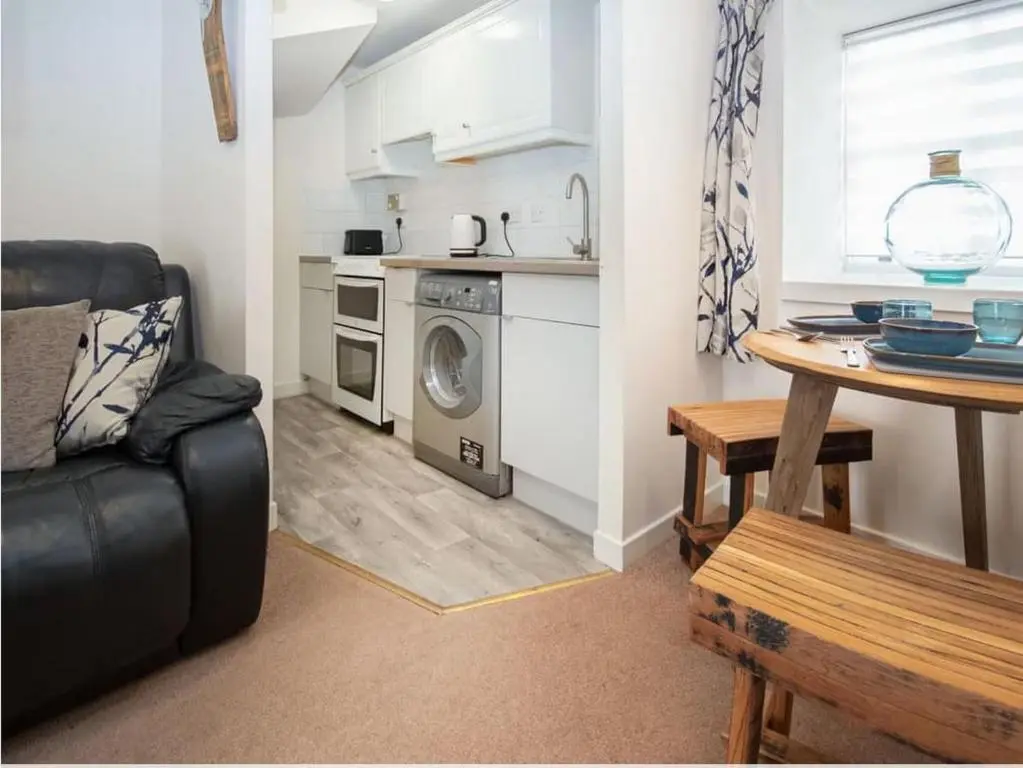 a living room with a couch and a table and a kitchen at 1 Bedroom Alexander Courtyard-Free Parking in Inverness