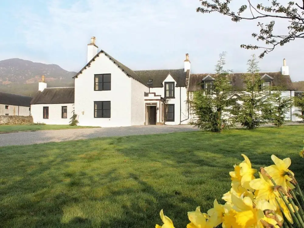 a white house with yellow flowers in front of it at Biallid House in Newtonmore