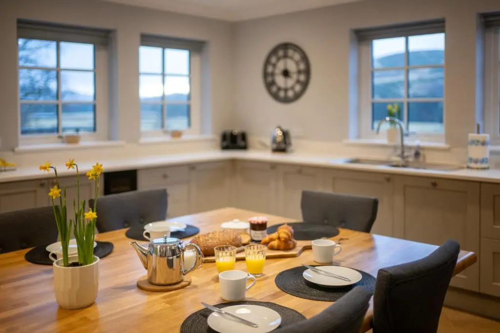 a kitchen with a wooden table with chairs and a dining room at Glenview in Tomatin
