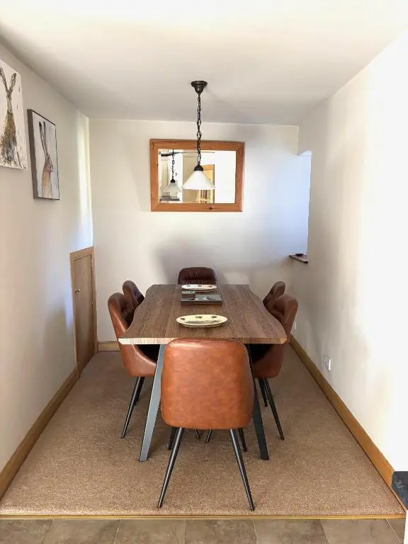 a dining room with a wooden table and chairs at Mary Cottage in Garmouth