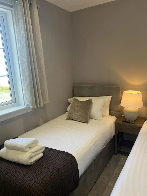 a small bedroom with a bed and a window at Tuckers Inn in Invergordon