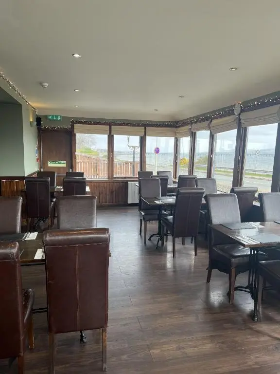a dining room with tables and chairs and windows at Tuckers Inn in Invergordon