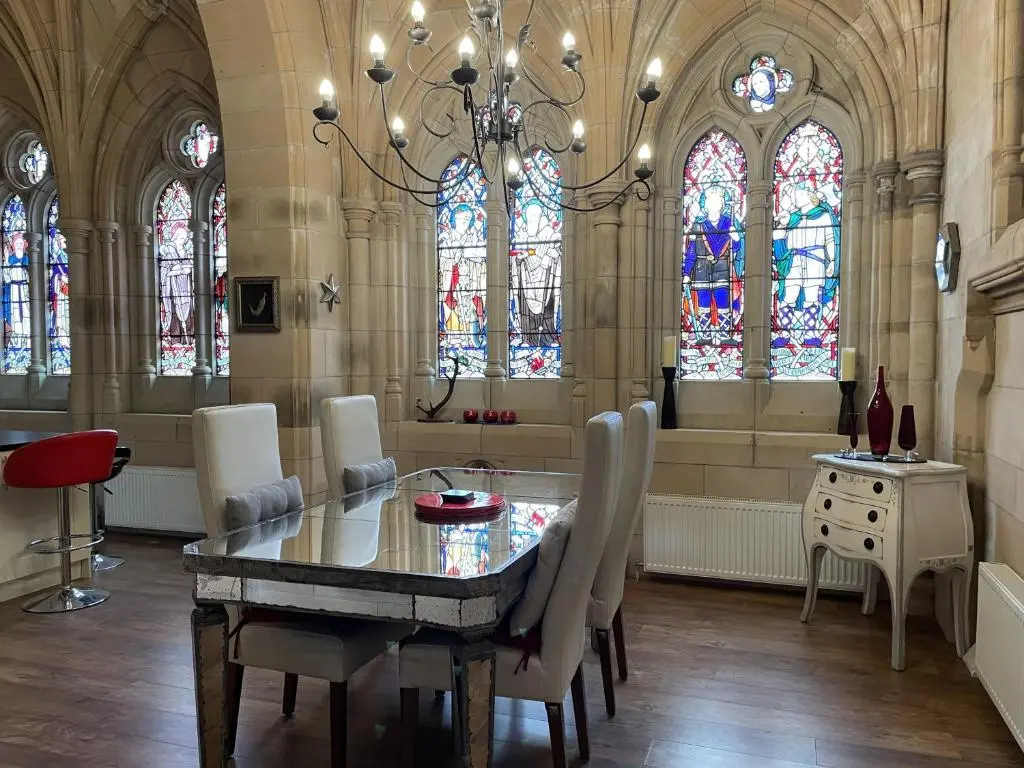 a dining room with a table and some stained glass windows at Romantic getaway at St Andrew's Chapel in Fort Augustus