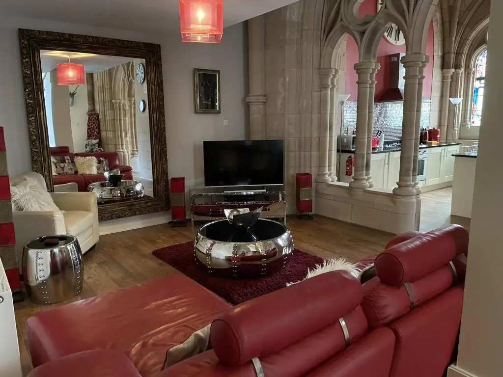 a living room with a red leather couch and a tv at Romantic getaway at St Andrew's Chapel in Fort Augustus