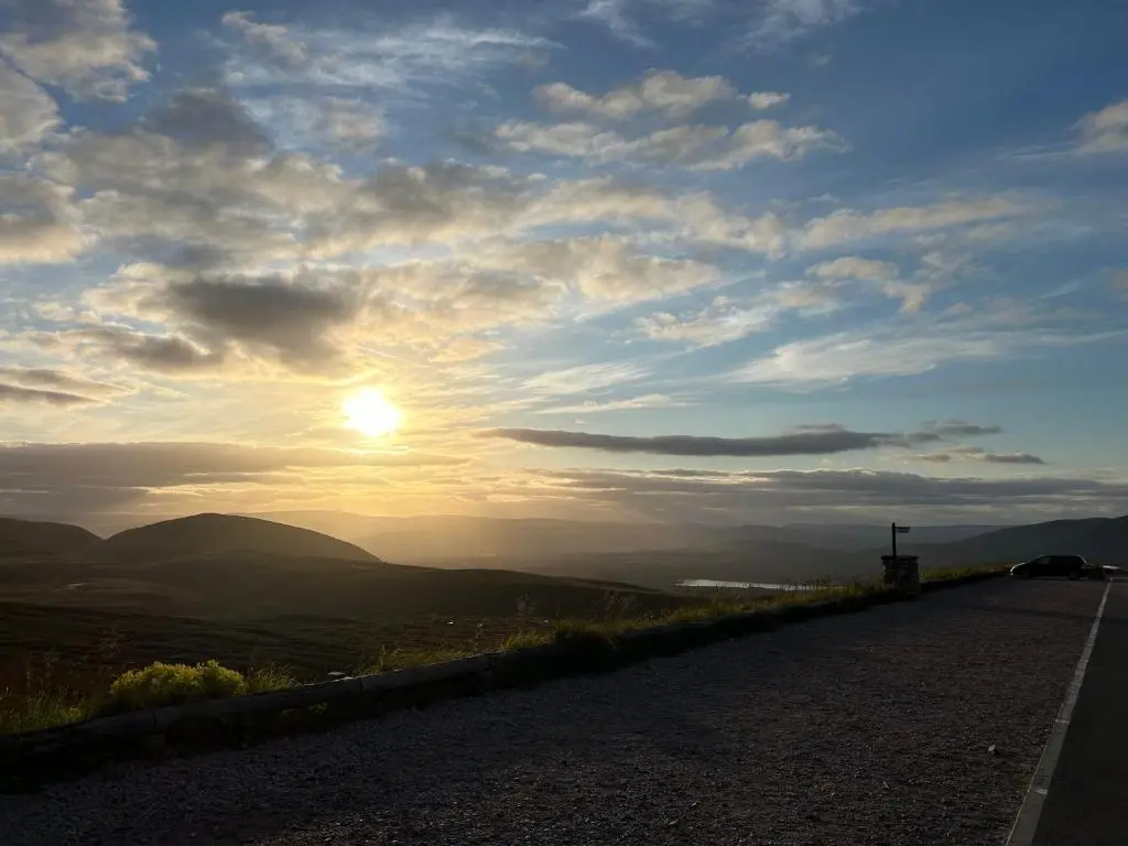 a road with the sun setting on the horizon at 6 Carn Dearg House in Aviemore