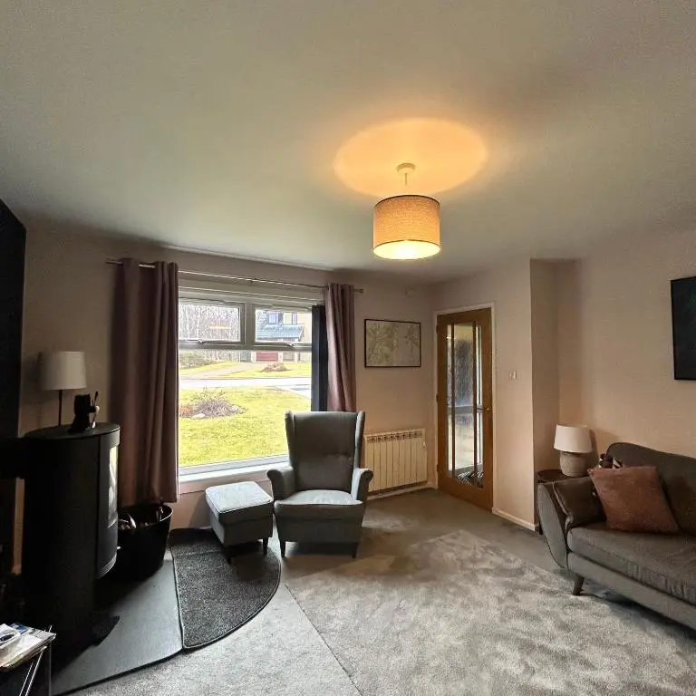 a living room with a couch and a chair and a tv at 6 Carn Dearg House in Aviemore