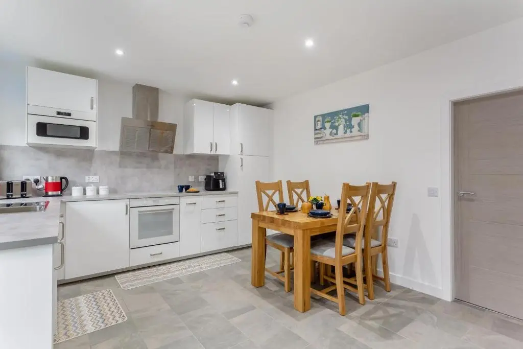 a kitchen with white cabinets and a wooden table and chairs at 2 Bed in Inverness oc-b32706 in Inverness