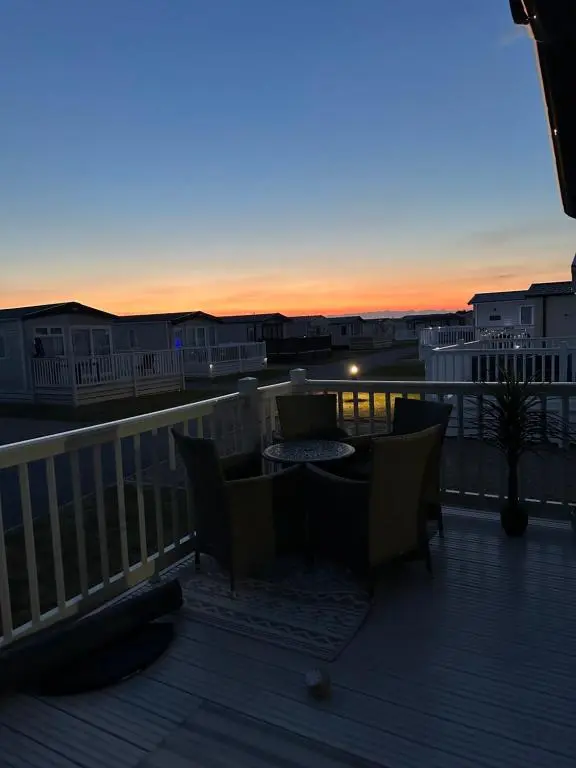 a deck with a table and chairs and a sunset at Jen's Retreat in Lossiemouth