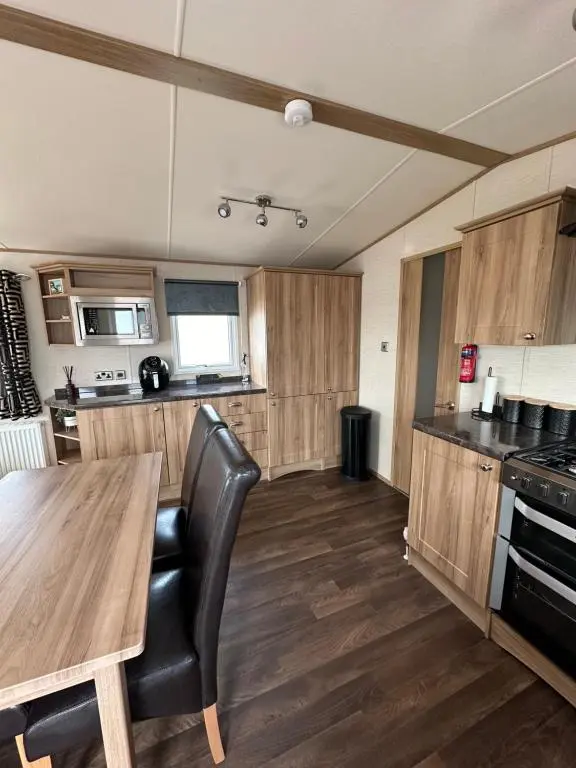 a kitchen with a wooden table and a wooden floor at Jen's Retreat in Lossiemouth