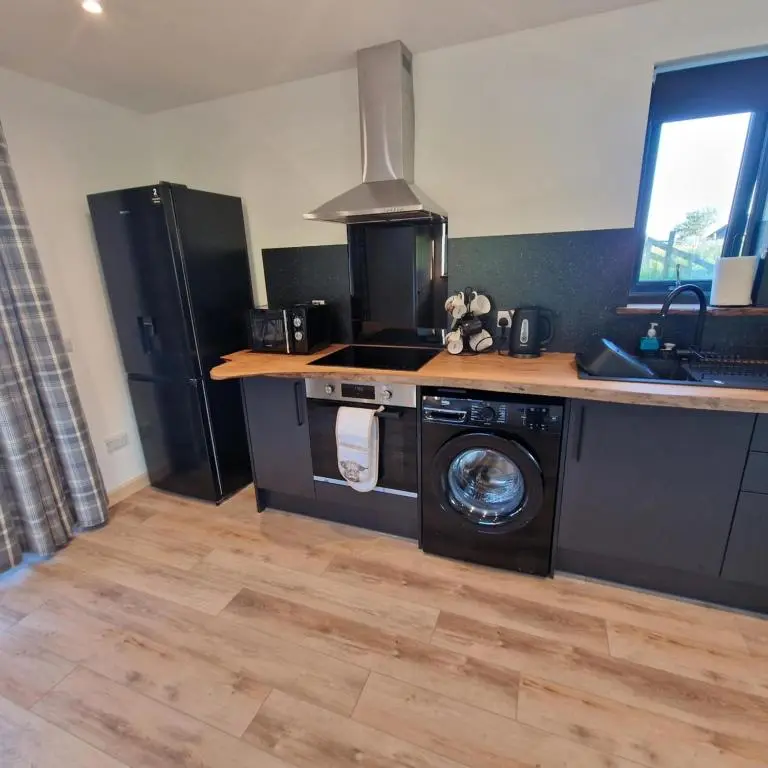 a kitchen with a stove and a washing machine at Temuka Lodge in Glenurguhart