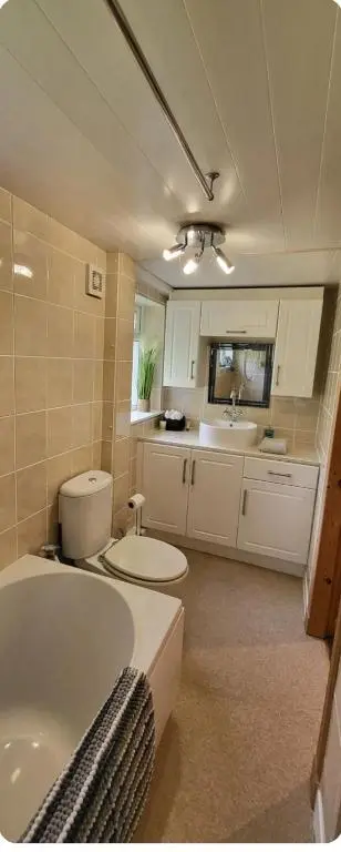 a bathroom with a tub and a toilet and a sink at Ghillies Cottage, Loch Ness in Milton