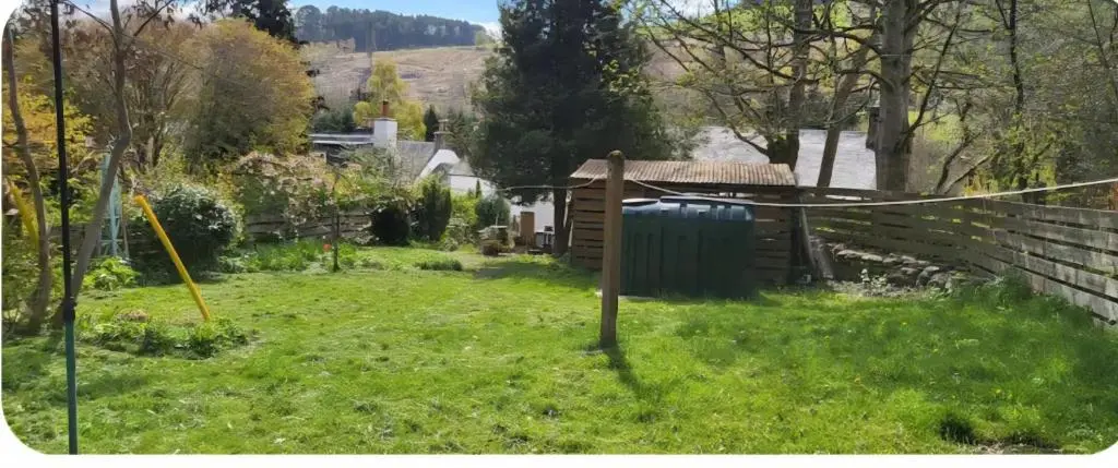 a yard with a fence and a house at Ghillies Cottage, Loch Ness in Milton