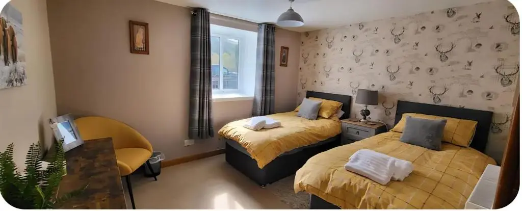 a bedroom with two beds and a window at Ghillies Cottage, Loch Ness in Milton