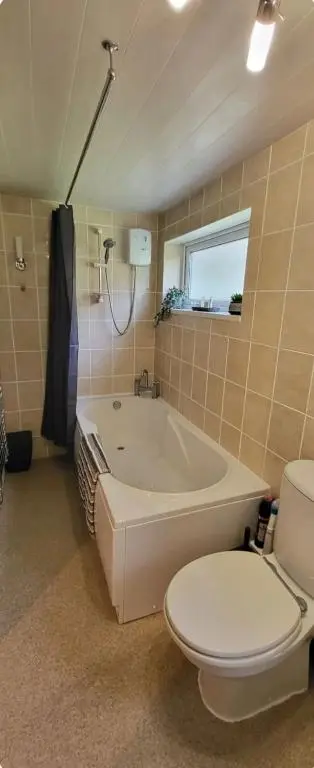 a bathroom with a tub and a toilet and a sink at Ghillies Cottage, Loch Ness in Milton