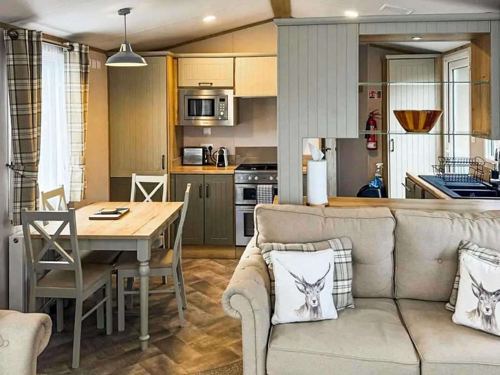 a living room and kitchen with a couch and a table at Lodge 58 in Aviemore