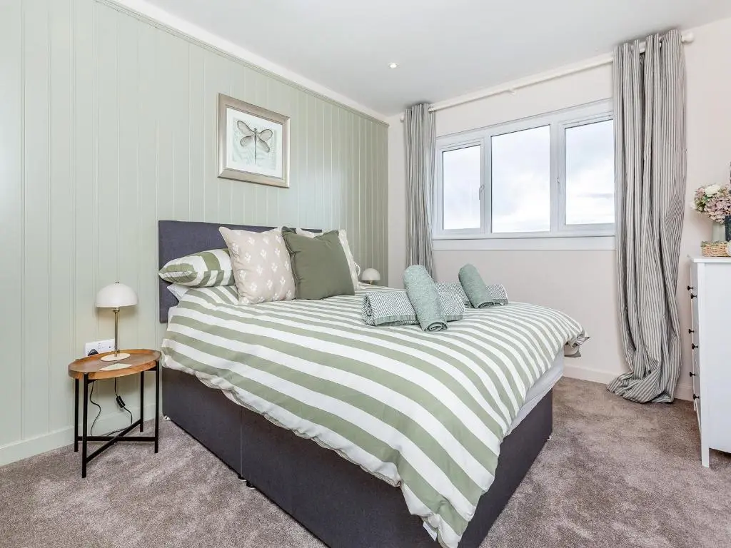 a bedroom with a large bed with a striped blanket at Sea Breezes in Balintore