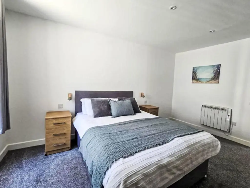 a bedroom with a large bed and a wooden night stand at Apartment Fishertown Apartment by Interhome in Nairn