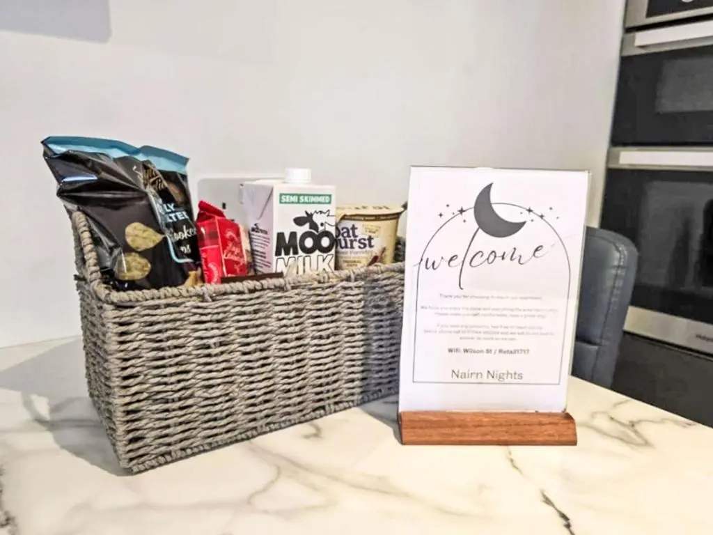a basket filled with snacks and a sign on a table at Apartment Fishertown Apartment by Interhome in Nairn