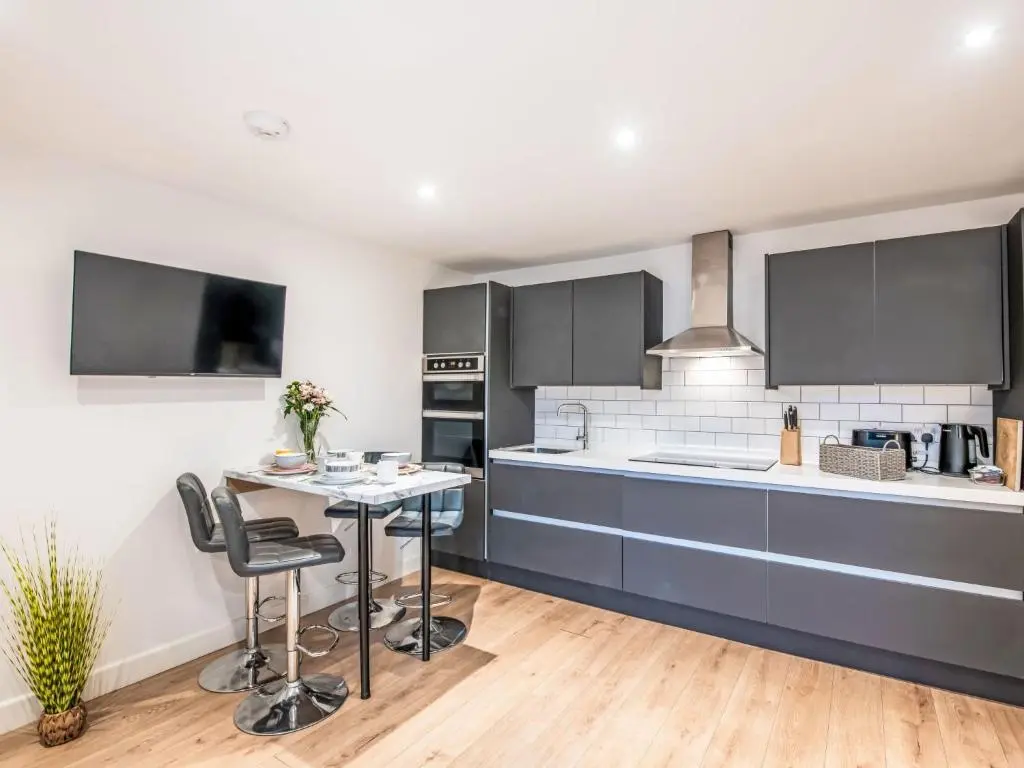 a kitchen with black cabinets and a table and chairs at Apartment Fishertown Apartment by Interhome in Nairn