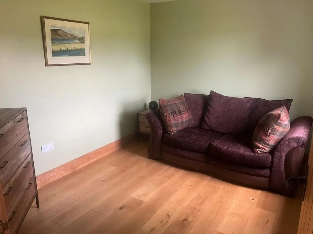 a living room with a purple couch and wooden floors at Dalvourn West Wing , Farr by Inverness in Tordarroch