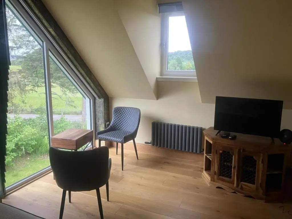 a living room with two chairs and a flat screen tv at Dalvourn West Wing , Farr by Inverness in Tordarroch