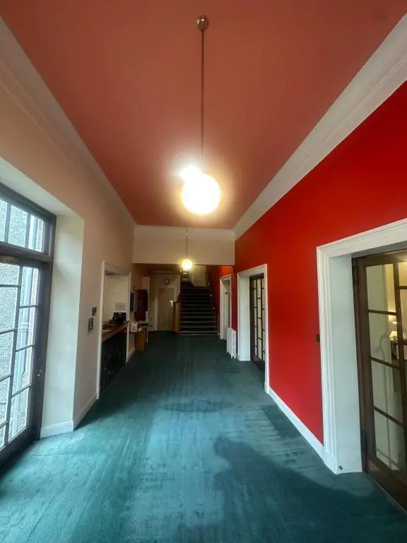 an empty room with a red wall and a hallway at Cluny Hill Hotel in Forres