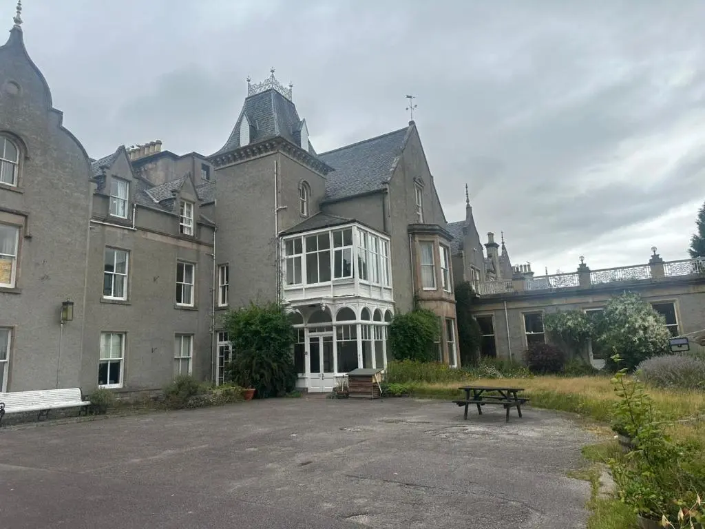 a large building with a picnic table in front of it at Cluny Hill Hotel in Forres