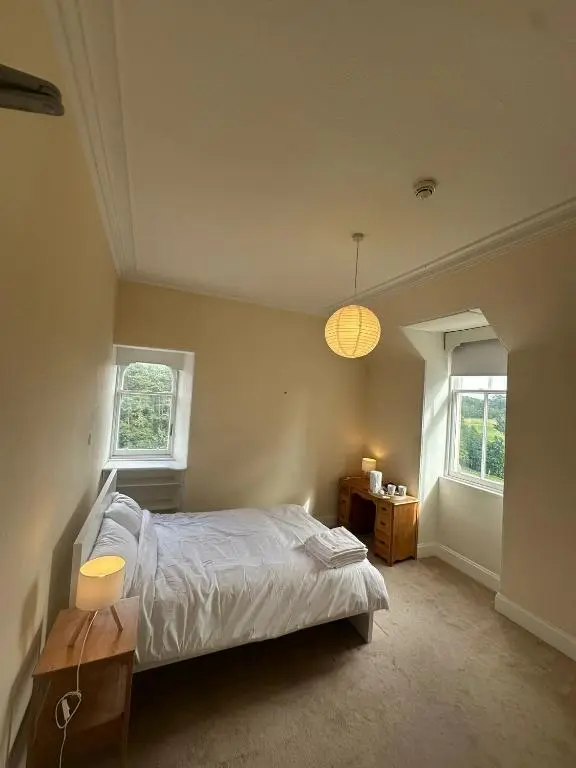 a bedroom with a bed and two windows at Cluny Hill Hotel in Forres