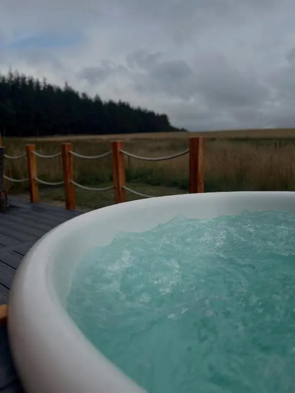 a bath tub filled with water in front of a fence at Barn Owl Pod - Speyside in Carron