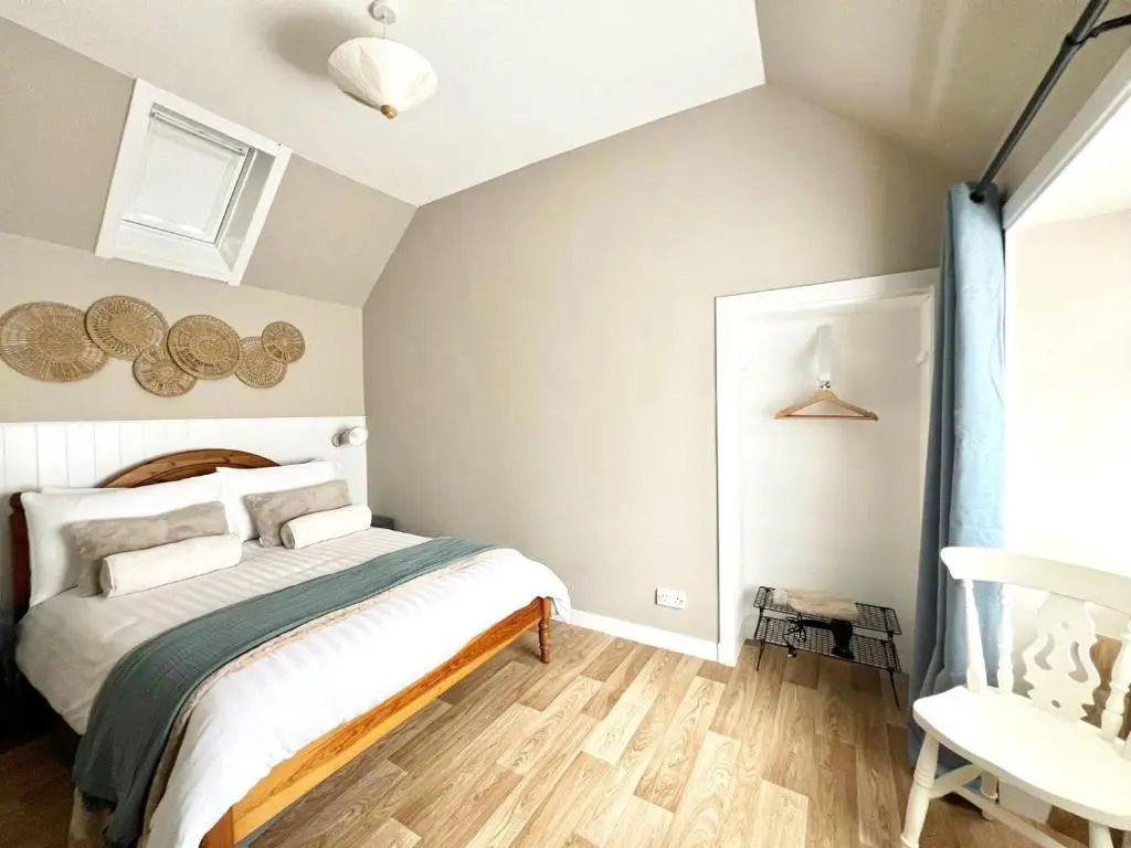 a bedroom with a bed and a chair at Seatown Cottage - Stone's throw from beach in Lossiemouth