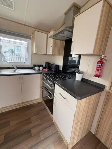 a kitchen with white cabinets and a stove top oven at Summer breeze in Lossiemouth