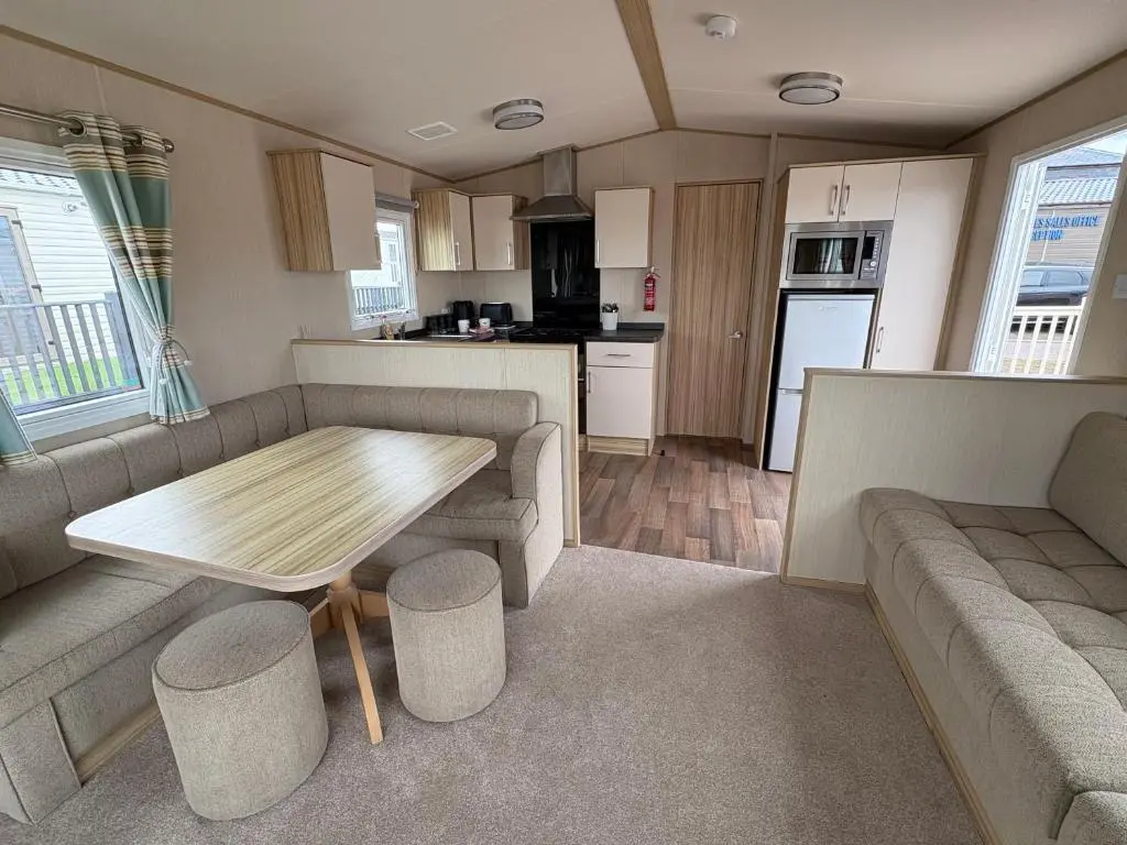 a living room with a table and a kitchen at Summer breeze in Lossiemouth