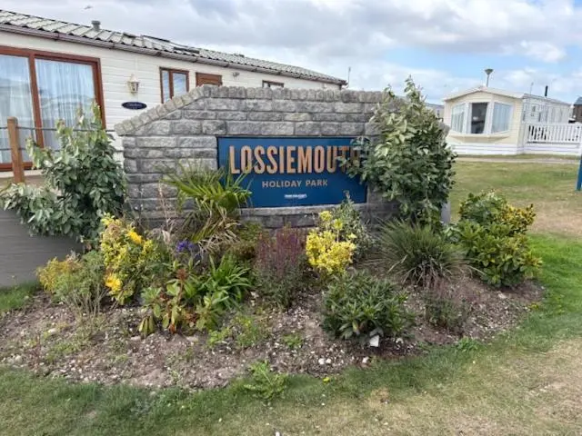a sign for a house with flowers in a yard at Summer breeze in Lossiemouth