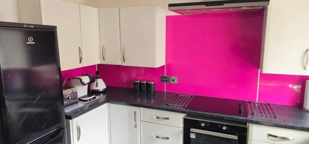 a kitchen with pink walls and white cabinets at Coastal Bliss, Rosehearty, Fraserburgh in Rosehearty