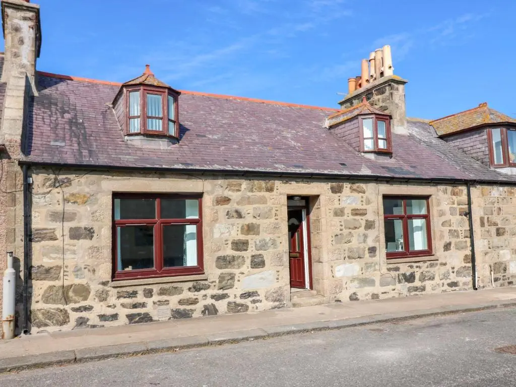 an old stone house with red windows on a street at No 9 North St in Fraserburgh