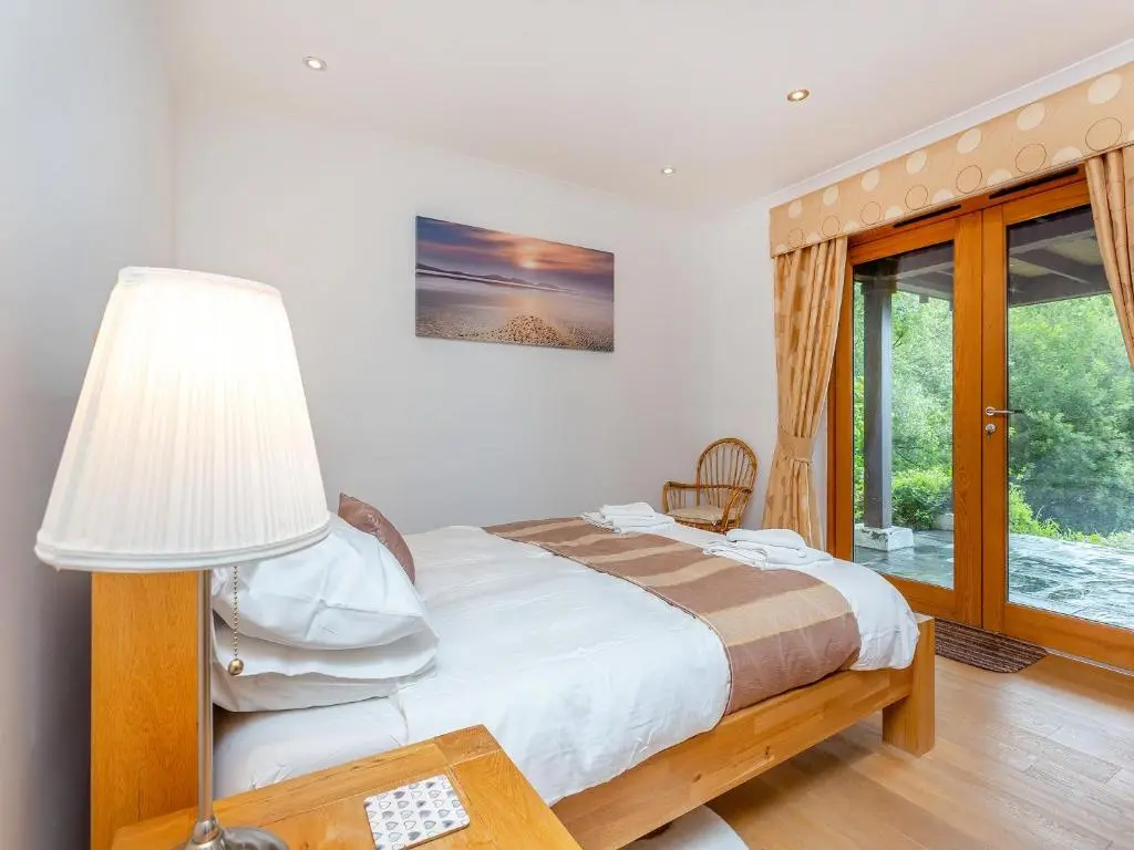 a bedroom with a bed with a lamp and a window at Corrie Burn Villa in Ullapool