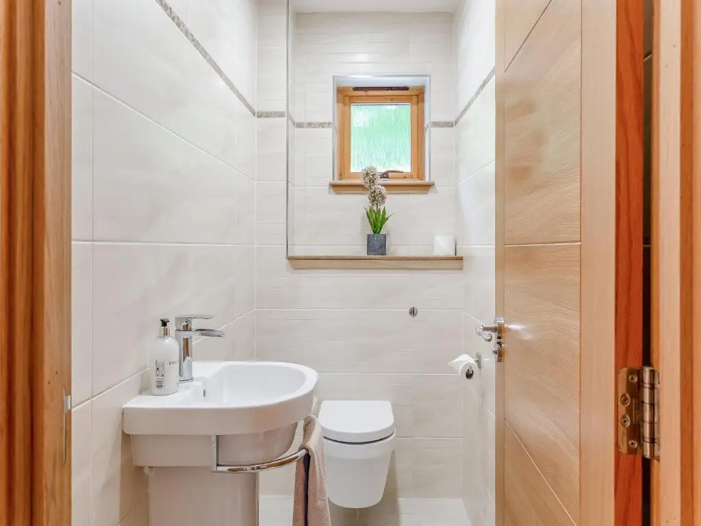 a white bathroom with a sink and a toilet at Corrie Burn Villa in Ullapool