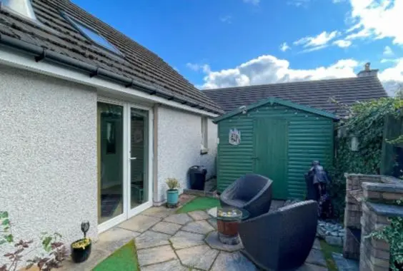 a yard with two chairs and a green shed at Birch Cottage in Aviemore