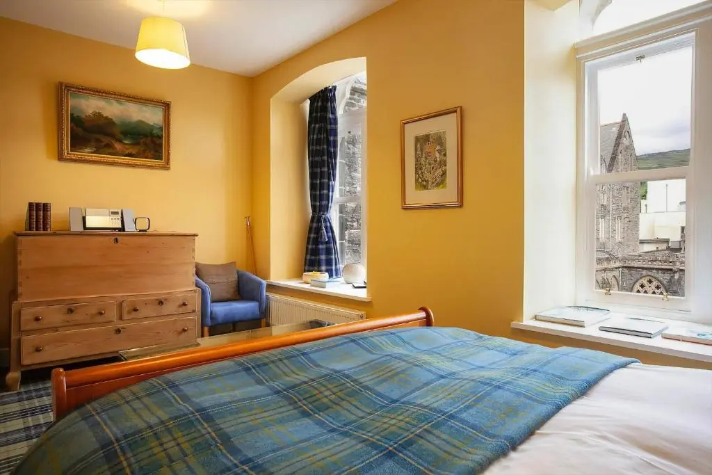 a bedroom with a bed and a dresser and a window at The Livingstone Loch Ness OS9 in Fort Augustus