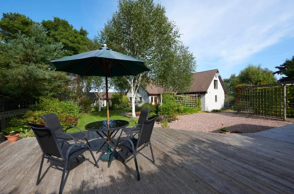 a table with two chairs and an umbrella on a deck at By the Brae in Inverness