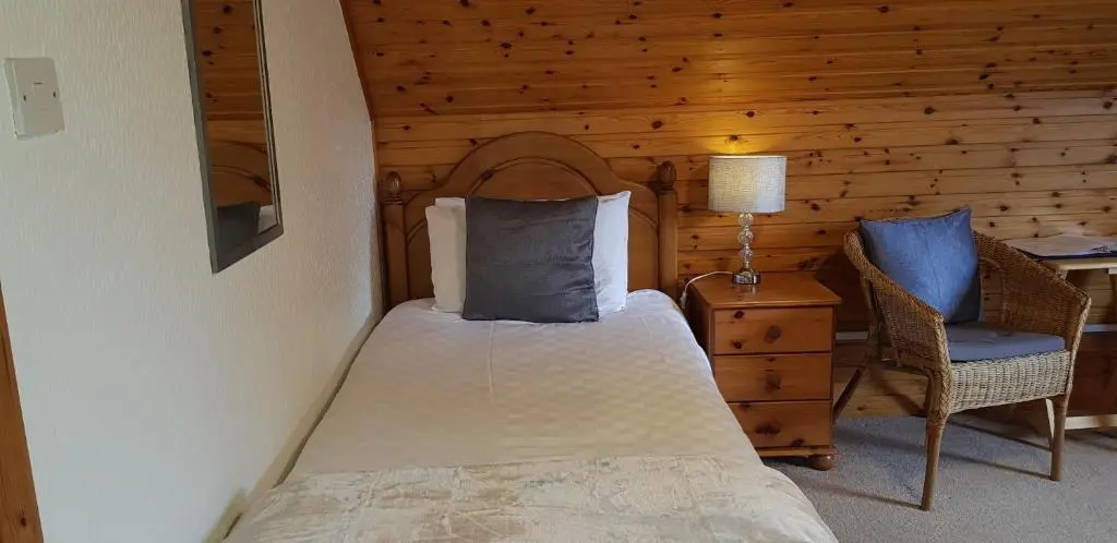 a bedroom with a bed and a table and a chair at Carn Mhor Bed and Breakfast in Aviemore
