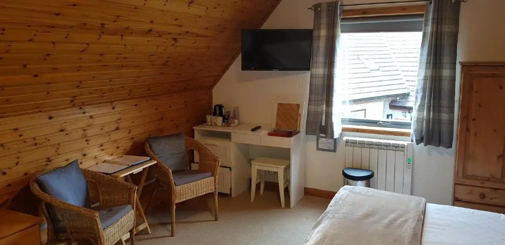 a room with a desk and chairs and a television at Carn Mhor Bed and Breakfast in Aviemore