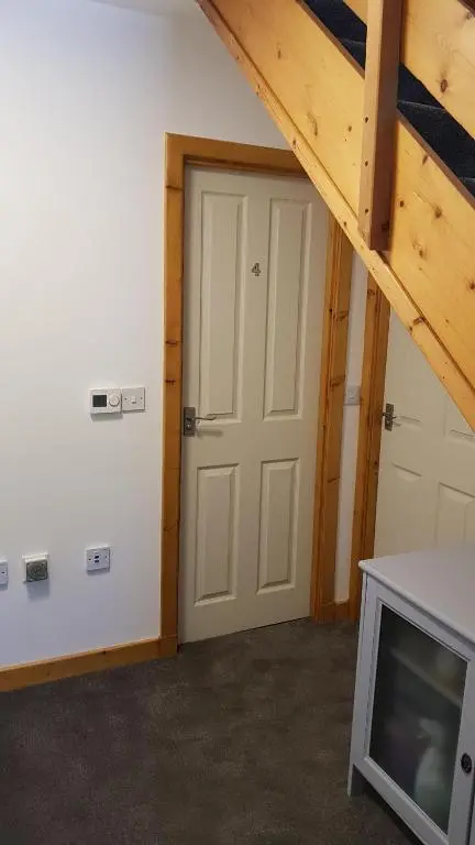 an attic room with a door and a tv at Carn Mhor Bed and Breakfast in Aviemore