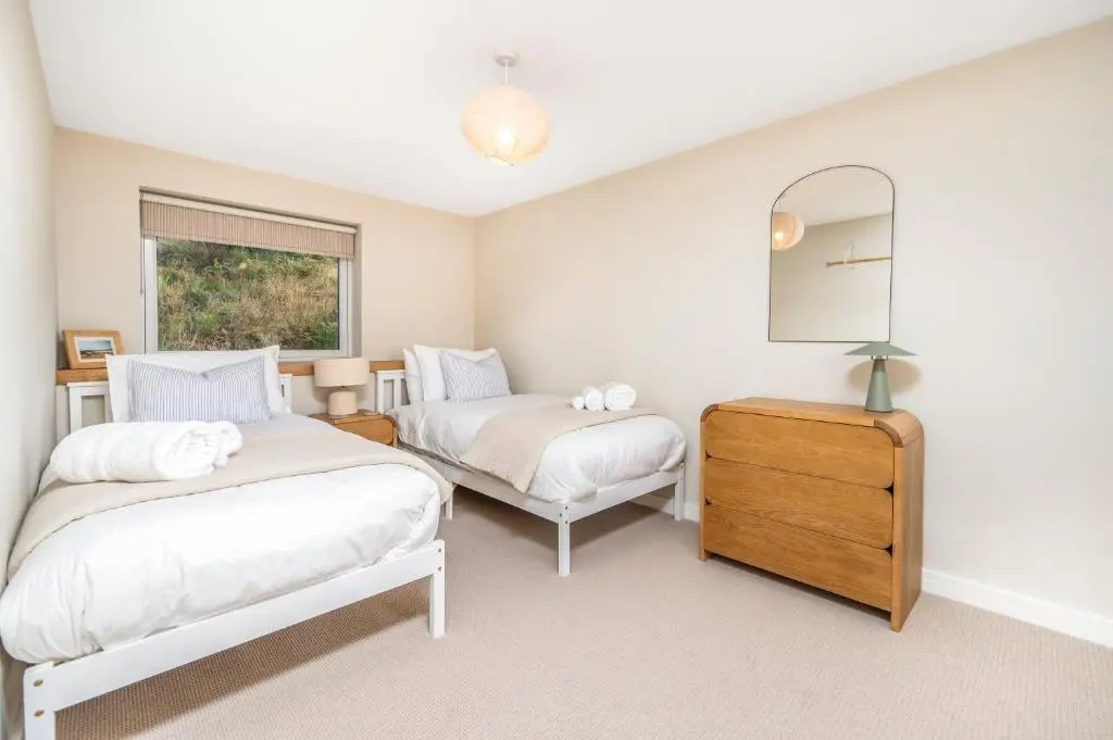 a bedroom with two beds and a mirror and a dresser at The Top House, Lothmore in Helmsdale