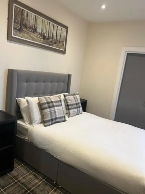 a bedroom with a large bed with white sheets and pillows at Royal Hotel in Dingwall