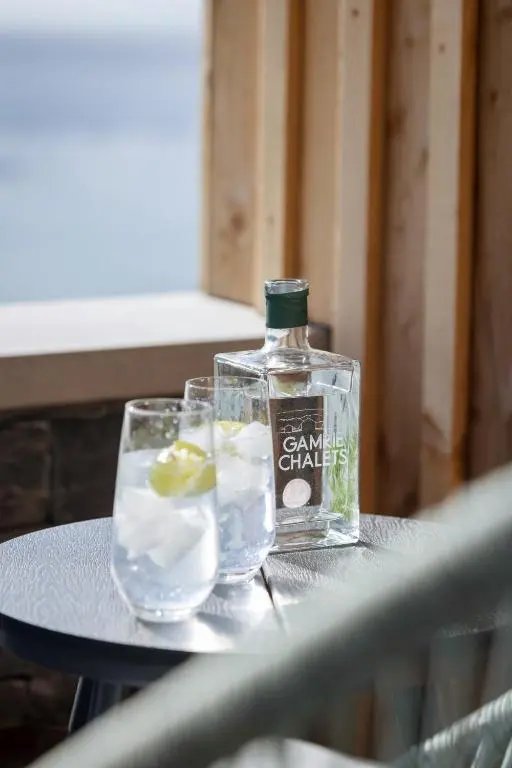 a bottle of gin sitting on a table with two glasses at Muckle View in Gardenstown