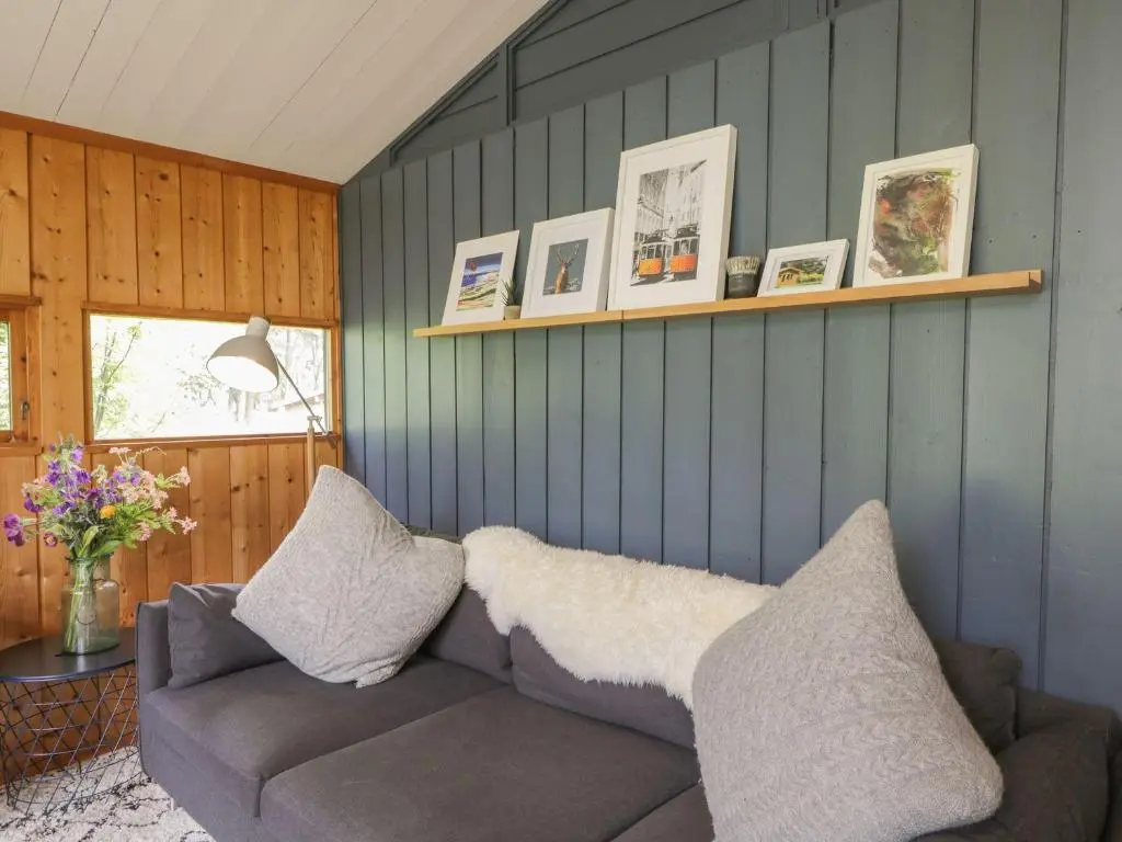 a living room with a gray couch and a window at Blue Pine Lodge in Dornoch