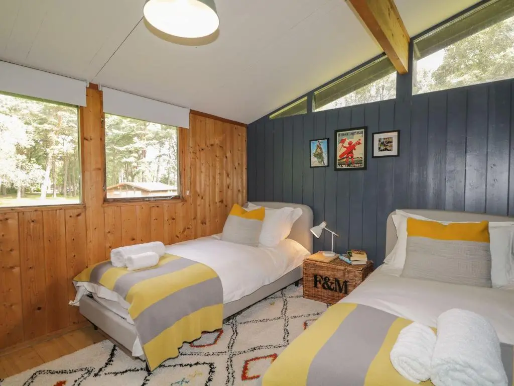 two beds in a room with blue walls and windows at Blue Pine Lodge in Dornoch