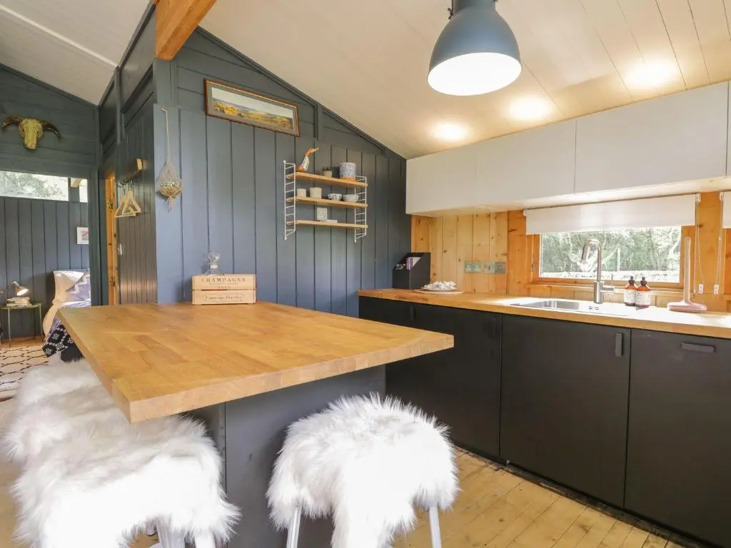 a kitchen with two white furry stools at a counter at Blue Pine Lodge in Dornoch