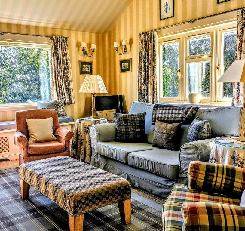 a living room with a couch and chairs and windows at Reids Cottage in Lairg